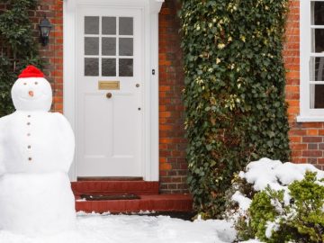 Real snowman outside house in winter scene